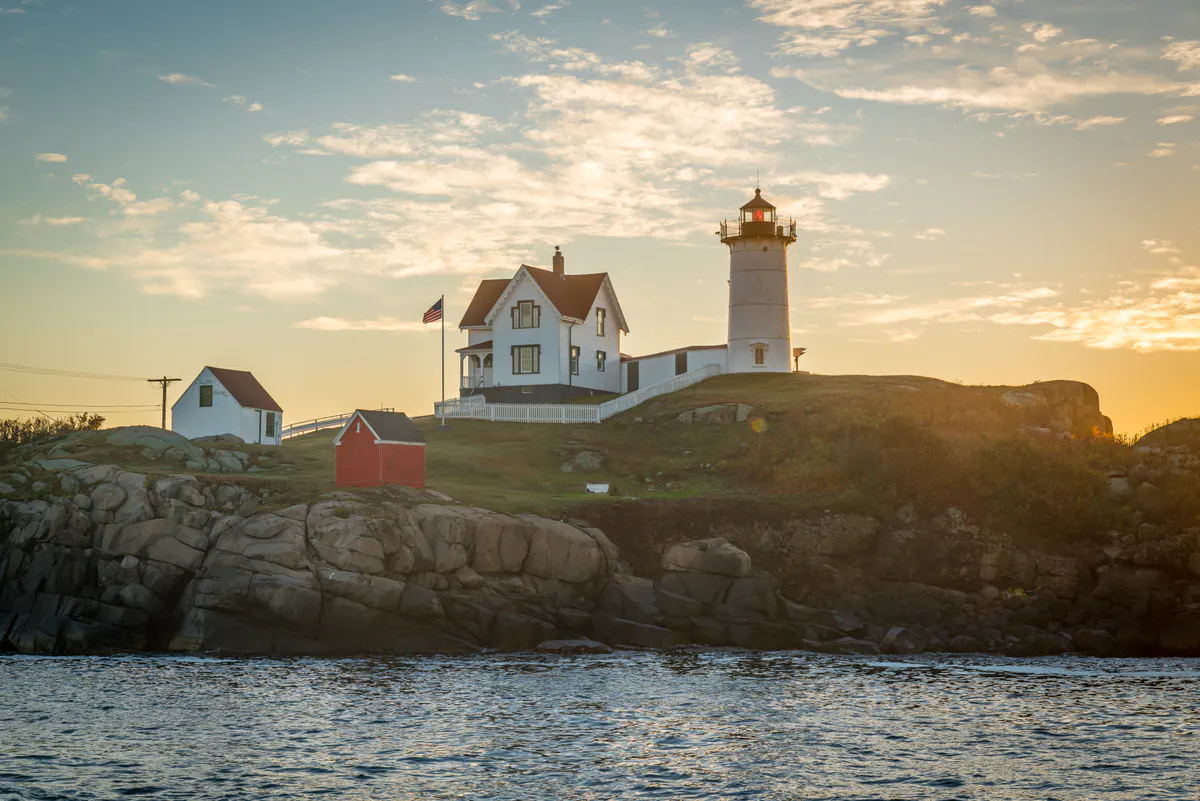 Nubble Light on Cape Neddick island in York, Maine, with red-roofed keeper's house and white tower on a rocky islet just offshore