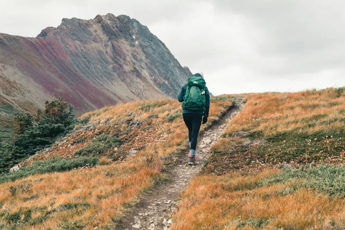 Hiker on a trail through fall foliage in the Maine mountains