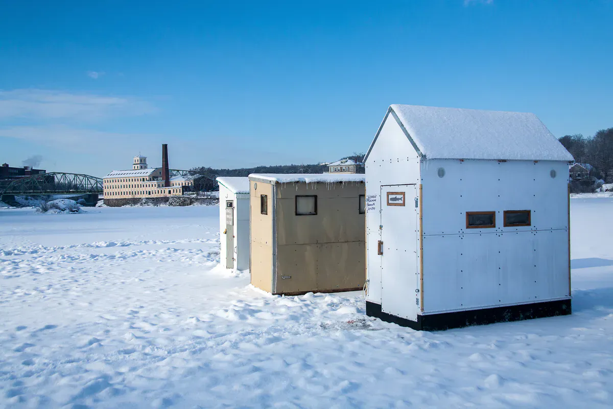 Three ice fishing houses on the frozen Androscoggin River that marks the border between Topsham and Brunswick, Maine